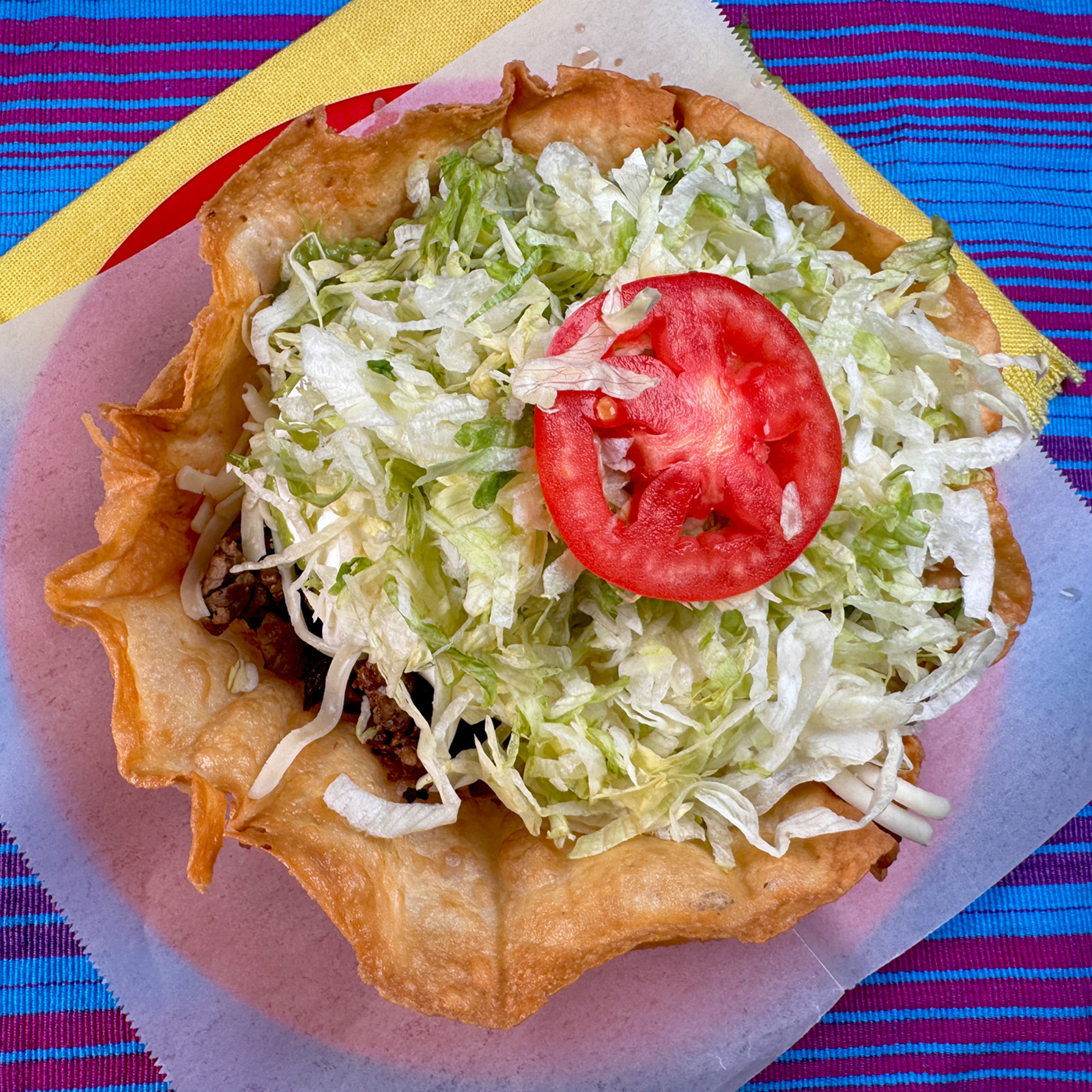 A crispy taco shell filled with fresh lettuce, seasoned meat, cheese, and salsa.